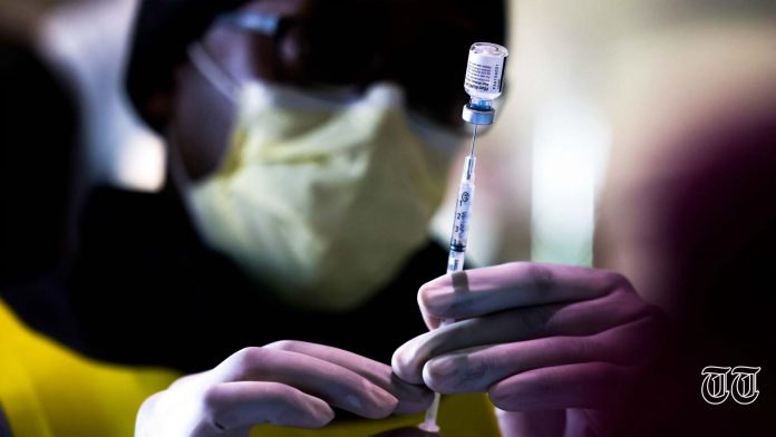 A file photo is shown of an individual preparing to administer a vaccination.