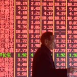A file photo is shown of a man in front of stock tickers.