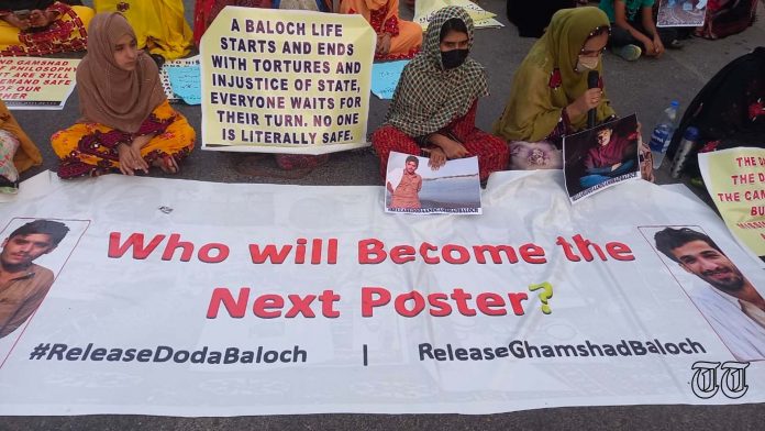 A file photo is shown of a poster at a protest calling for the release of Doda Baloch and Ghamshad Baloch.