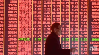 A file photo is shown of a man in front of stock tickers.