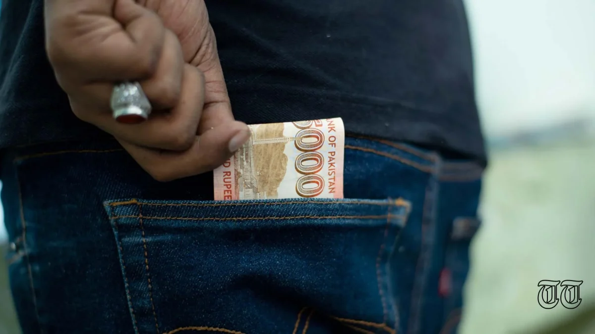 A file photo shows an individual discreetly pocketing a PKR5000 note.
