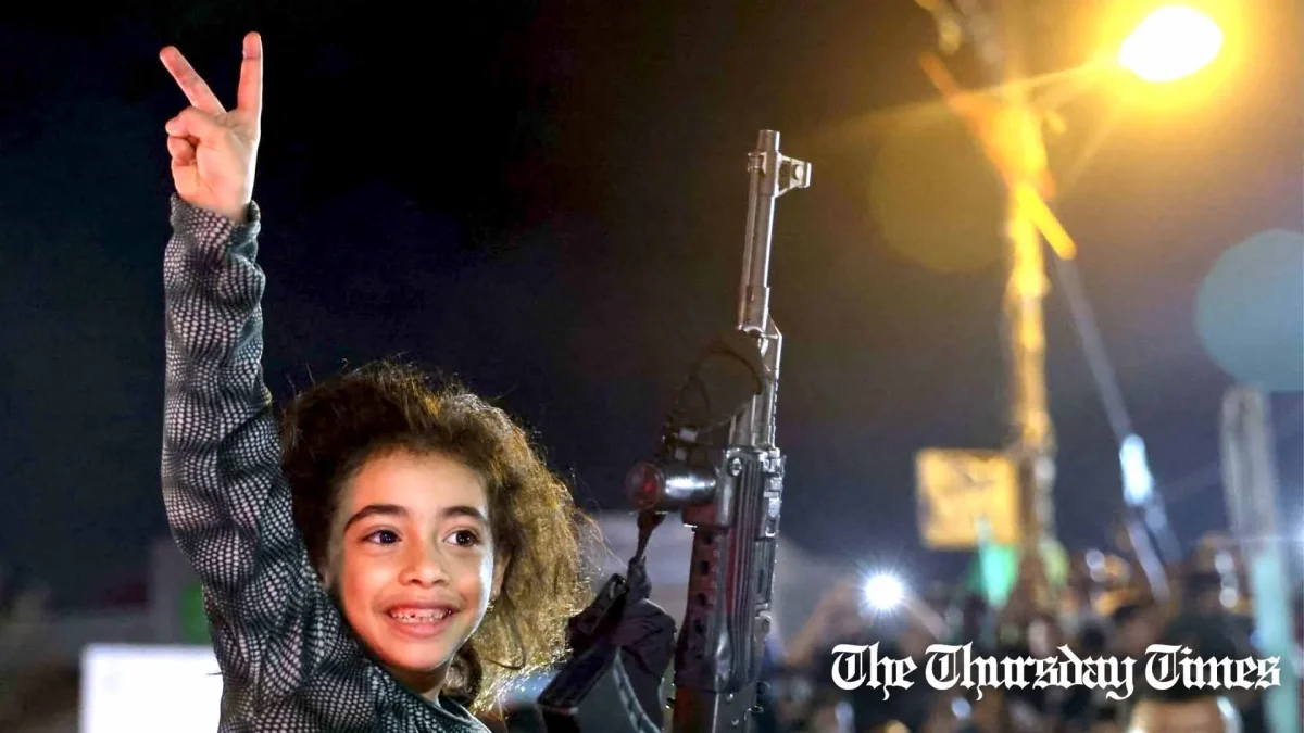 A file photo shows a child next to an automatic rifle flashing the victory sign at Rafah on May 21, 2021. — AFP