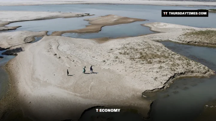 People walk across a dry sandbank in the Indus River