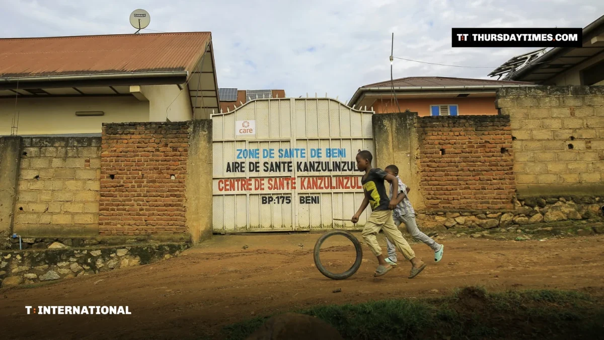 Children run past the gate of a health centre in Beni, eastern Congo