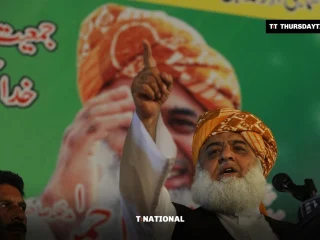 Maulana Fazlur Rehman in an orange turban raises a finger as he speaks at a rally