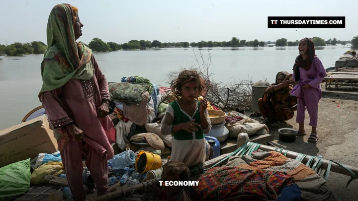 A woman and children sit among their belongings beside floodwater in Punjab