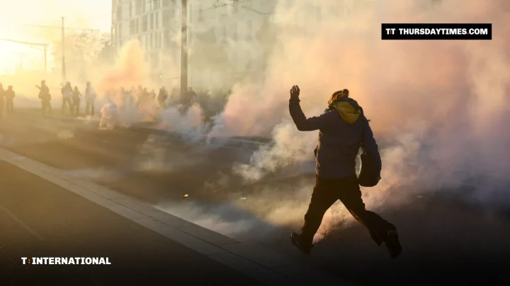 A protester runs through clouds of tear gas on a Paris street