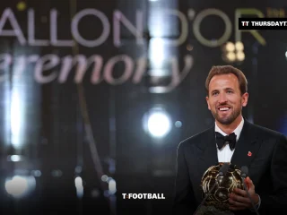Harry Kane smiles holding the Ballon d’Or trophy on stage in London