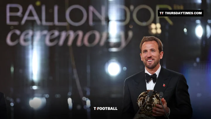 Harry Kane smiles holding the Ballon d’Or trophy on stage in London