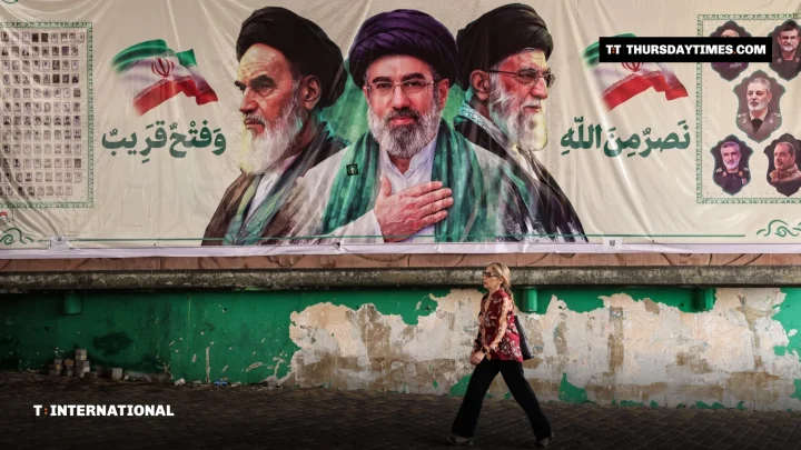A woman walks past a large mural of Iranian leaders in Tehran
