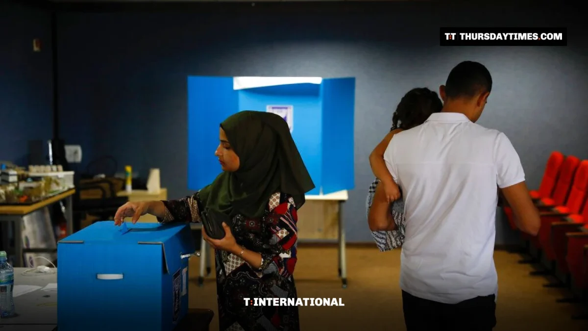 A woman in a headscarf drops her ballot into a blue box at a polling station in Kfar Manda, Israel