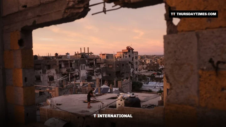 A man on a rooftop in the damaged Jabalia refugee camp seen through a broken wall
