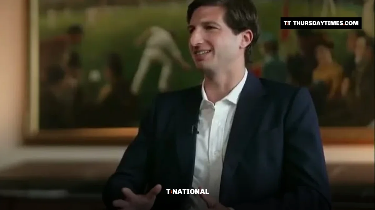 Sulaiman Isa Khan in a navy suit gestures while speaking during a TV interview