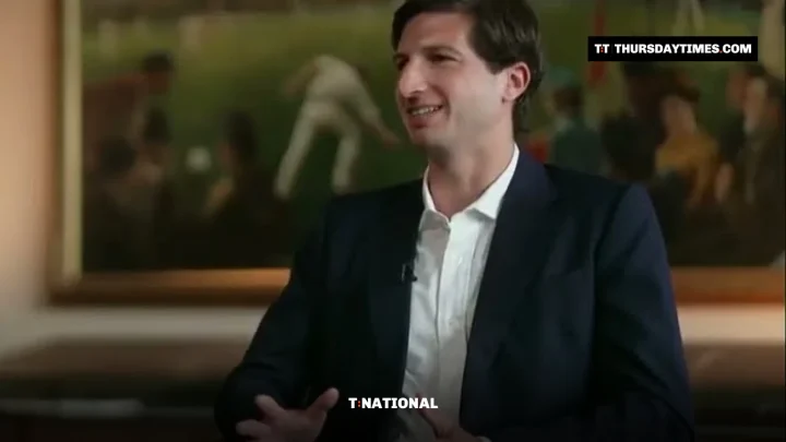 Sulaiman Isa Khan in a navy suit gestures while speaking during a TV interview