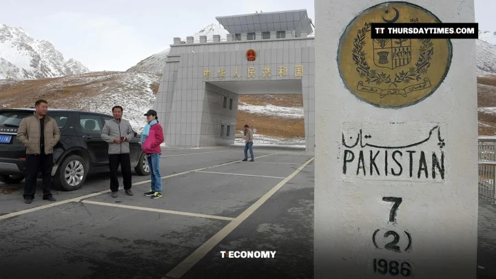 Chinese visitors beside a car at the Khunjerab border gate, next to a Pakistan boundary pillar with the state emblem