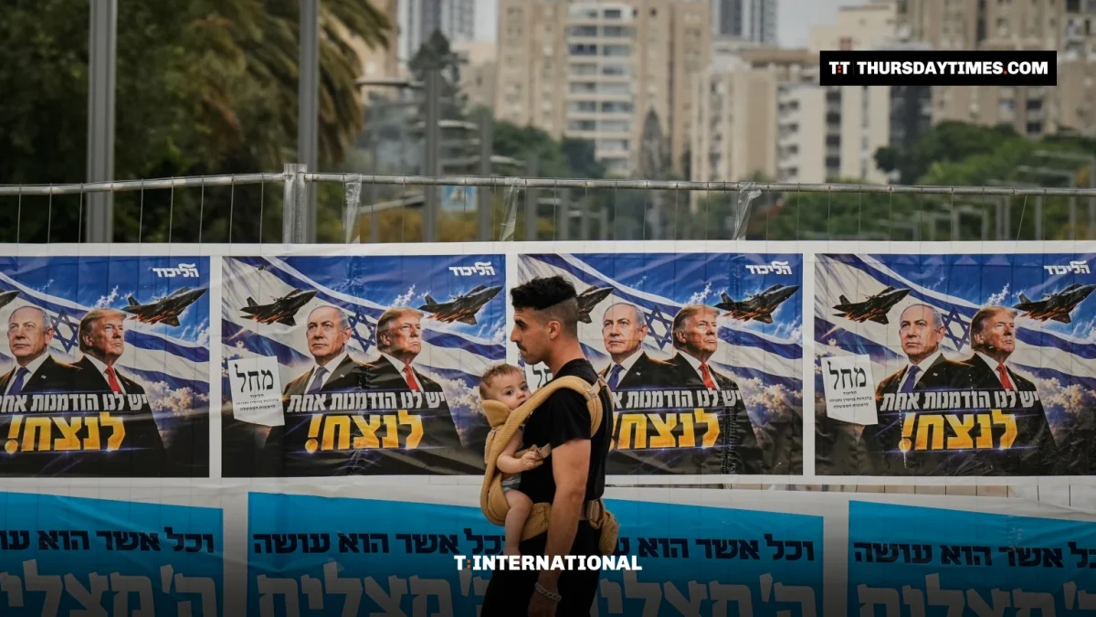A man carrying a child walks past Likud campaign banners showing Netanyahu and Trump