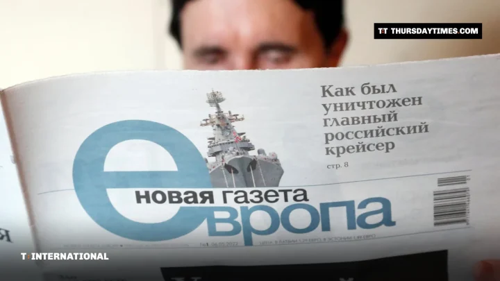 A reader holds up a copy of Novaya Gazeta Europe