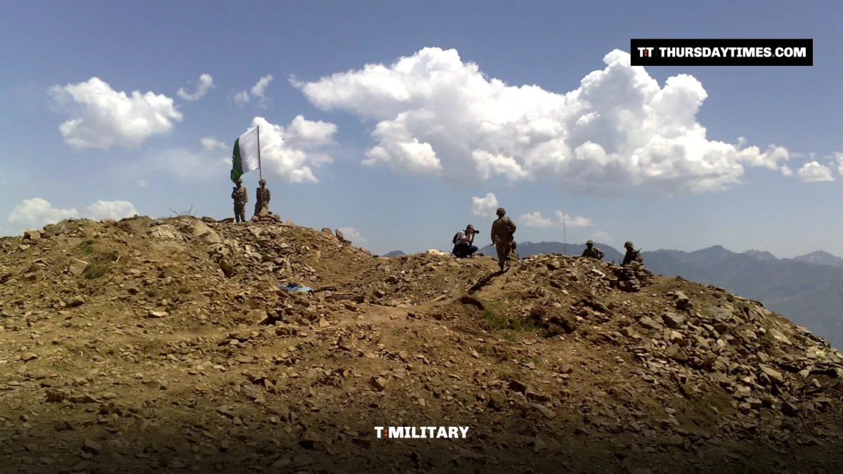 Pakistani soldiers and a national flag on a rocky hilltop post