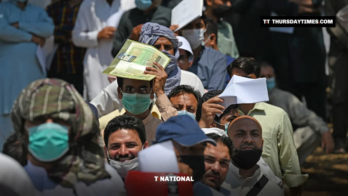 People in a queue hold up green Pakistani passports and documents