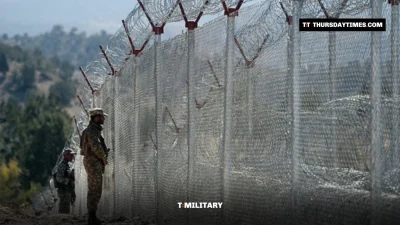 Pakistani soldiers stand beside a barbed-wire border fence on a hillside at Angoor Adda