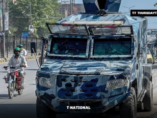 A motorcyclist drives past an armoured police vehicle on a Peshawar road