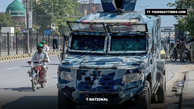 A motorcyclist drives past an armoured police vehicle on a Peshawar road