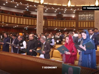 Lawmakers stand at their desks holding green folders as they take the oath in the Punjab Assembly chamber