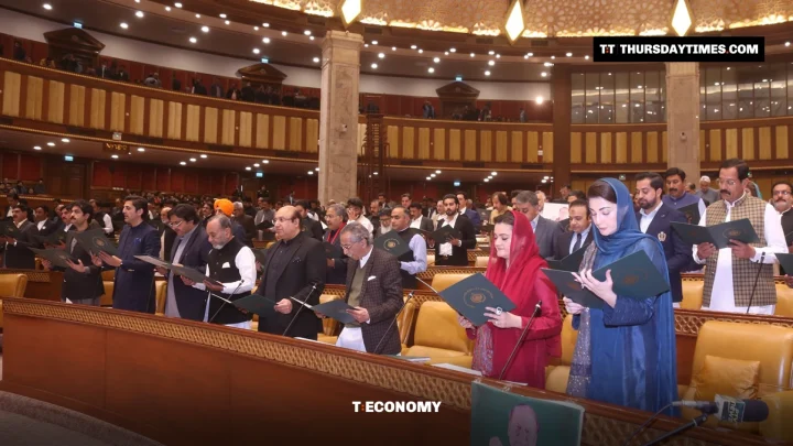 Lawmakers stand at their desks holding green folders as they take the oath in the Punjab Assembly chamber