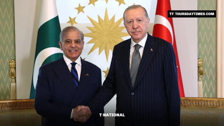 Shehbaz Sharif and Recep Tayyip Erdogan shake hands in front of Pakistani and Turkish flags