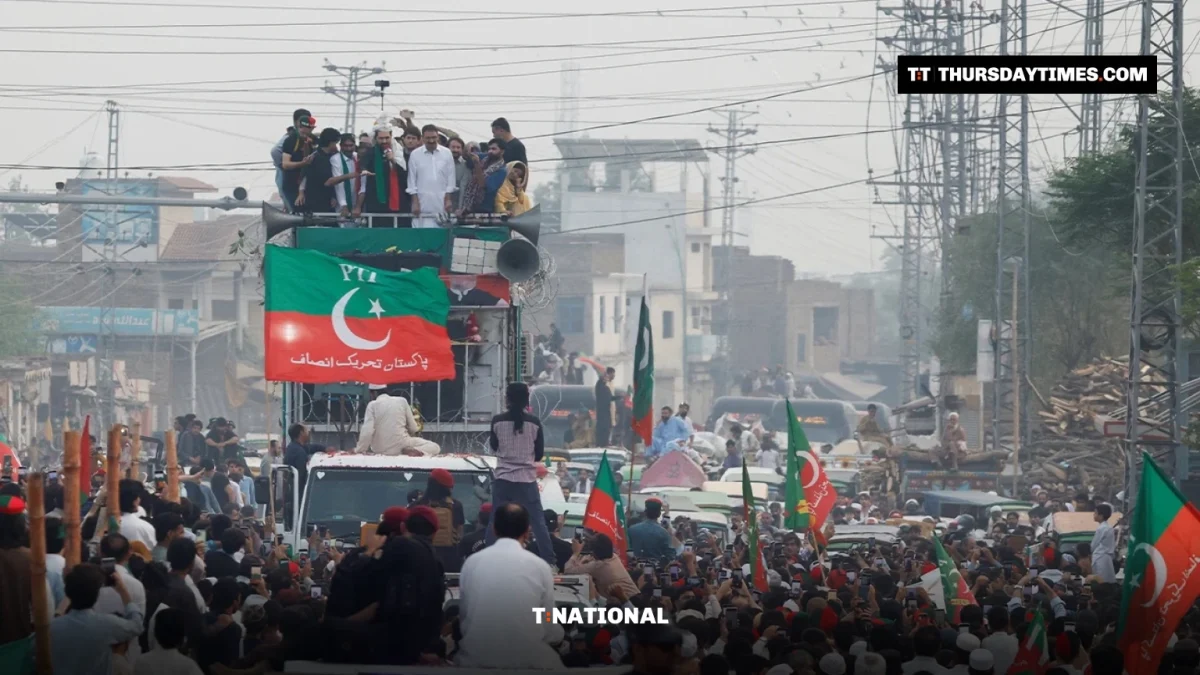 Crowds with PTI flags surround a container during a protest march near Peshawar