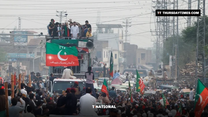 Crowds with PTI flags surround a container during a protest march near Peshawar