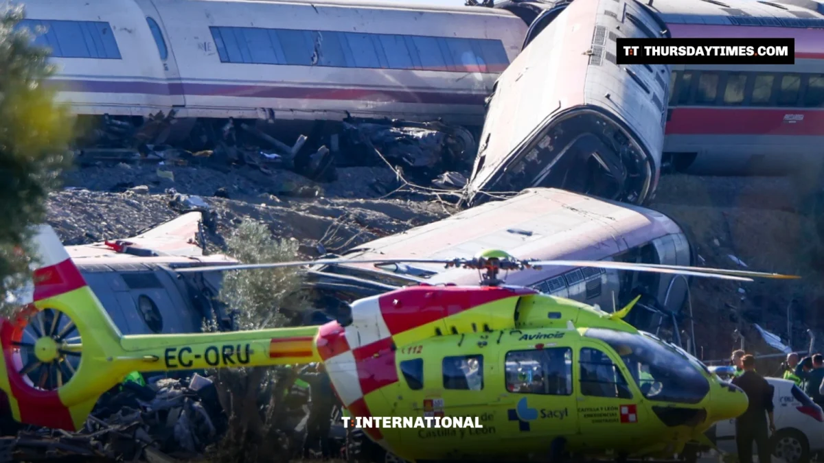 A yellow medical helicopter sits in front of crumpled high-speed train carriages near Urda