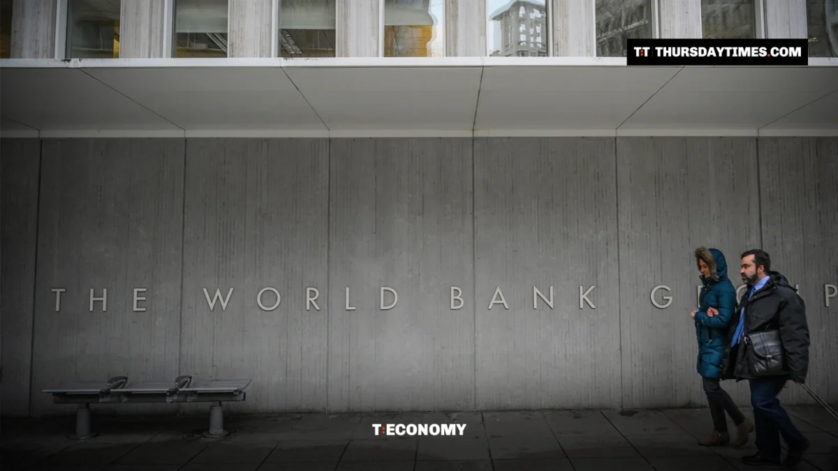 Two people walk past the World Bank Group lettering on the wall of its Washington headquarters